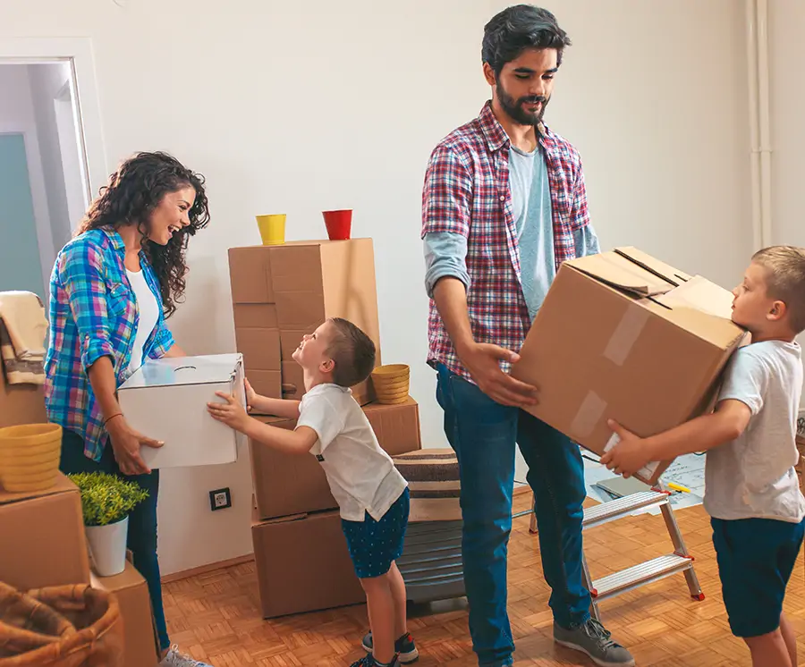 A family carrying moving boxes into their next home