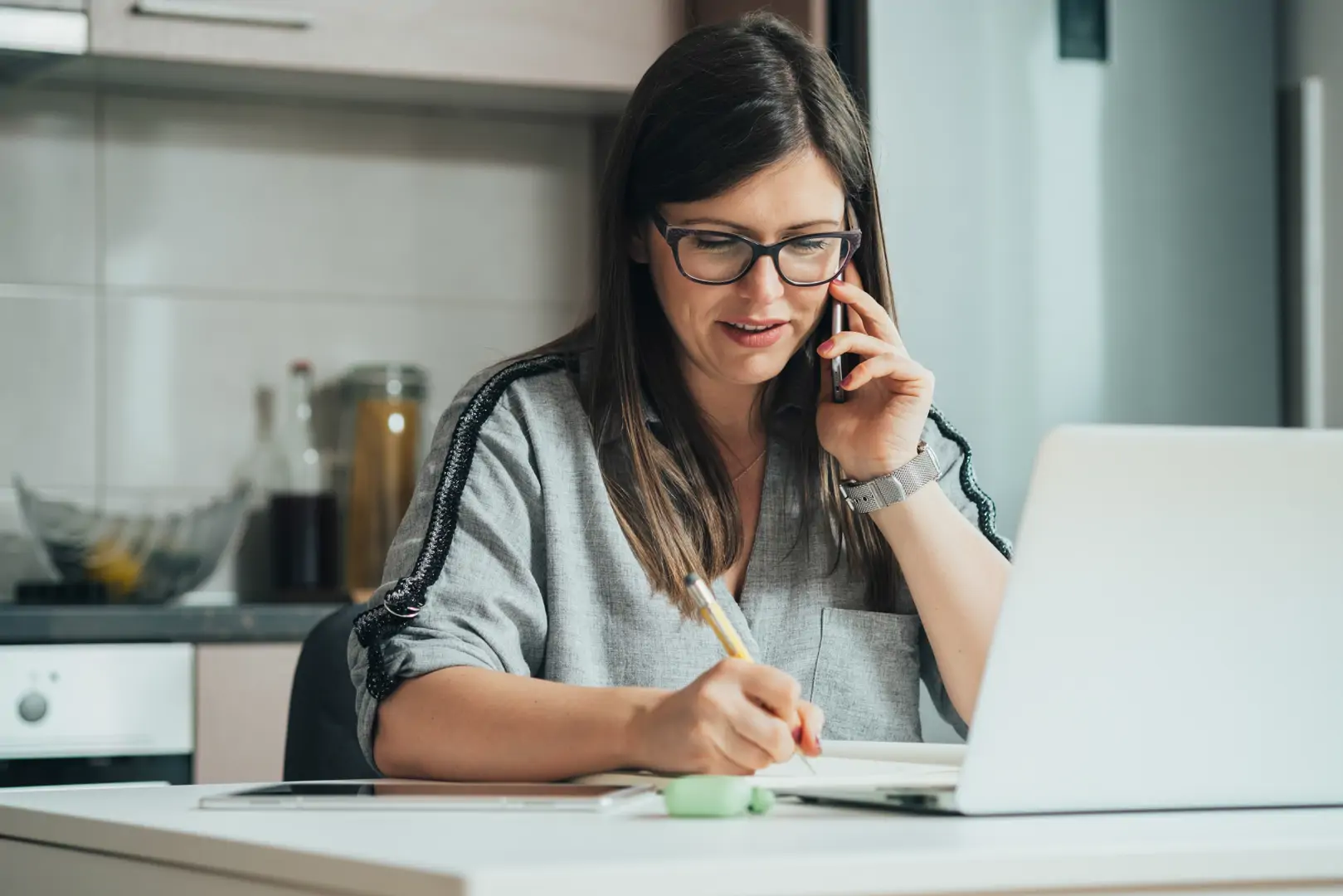 A person on the phone taking notes, calm and supported